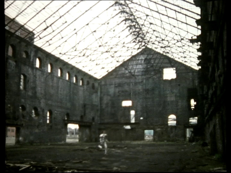 Vinni running across a concrete warehouse missing its roof