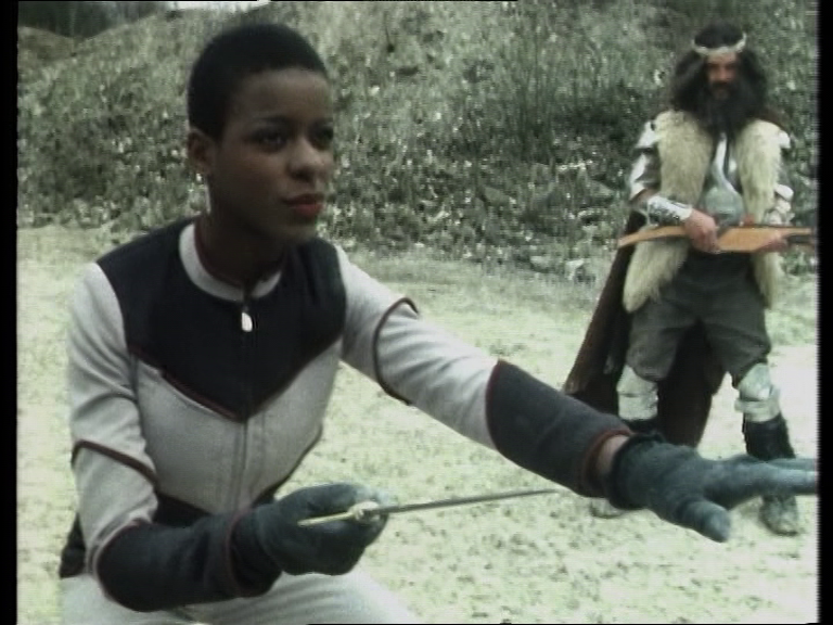 Dayna holding a small dagger, poised to move in during the fight