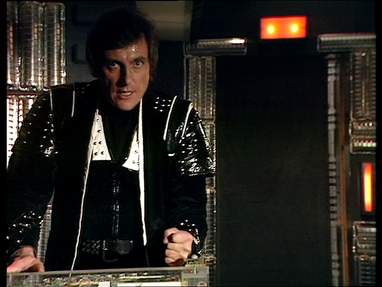 Avon standing over Orac as the door closes behind him