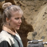 Soolin pointing a gun off screen