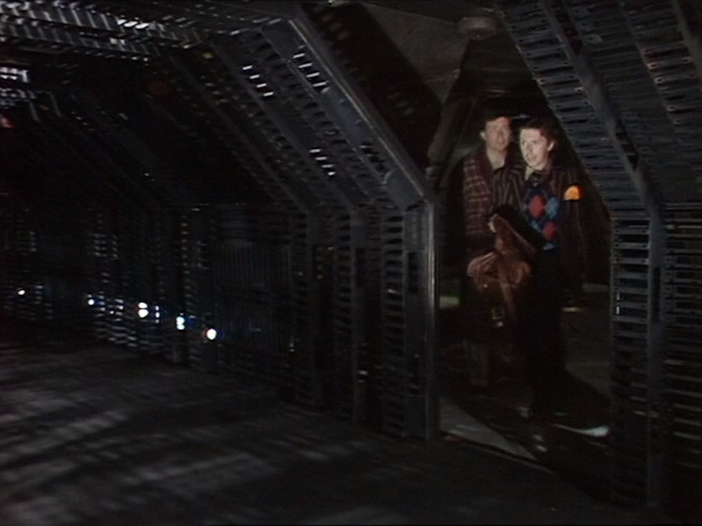 ford and arthur in doorway to dreary corridor