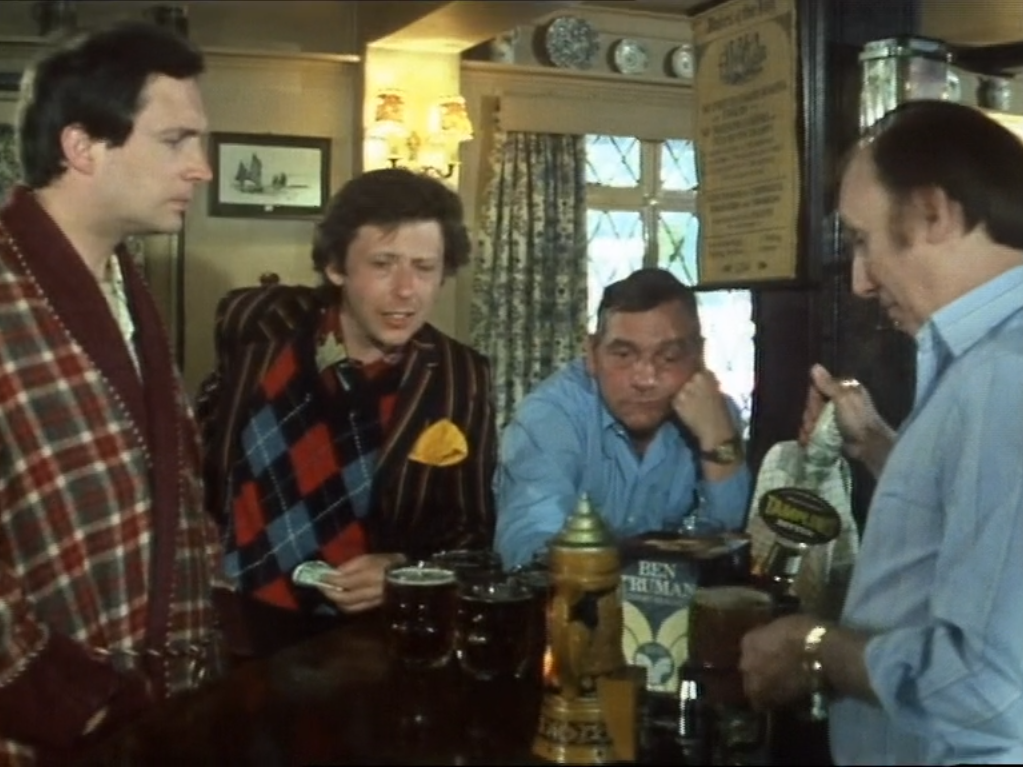 arthur and ford stand at the bar while their pints are pulled
