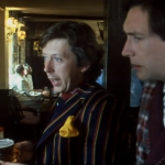 arthur and ford stand with their pints in the pub