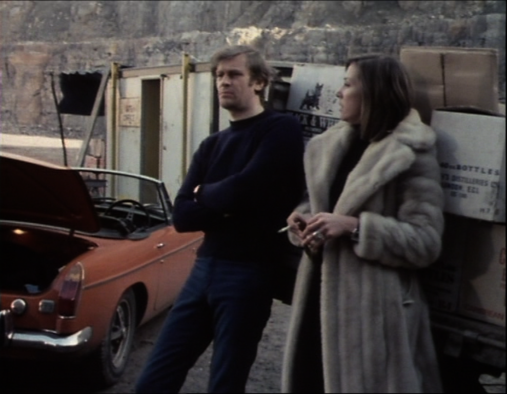greg and anne stand outside the hut beside boxes of booze