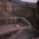 a hut sits in the middle of a giant quarry