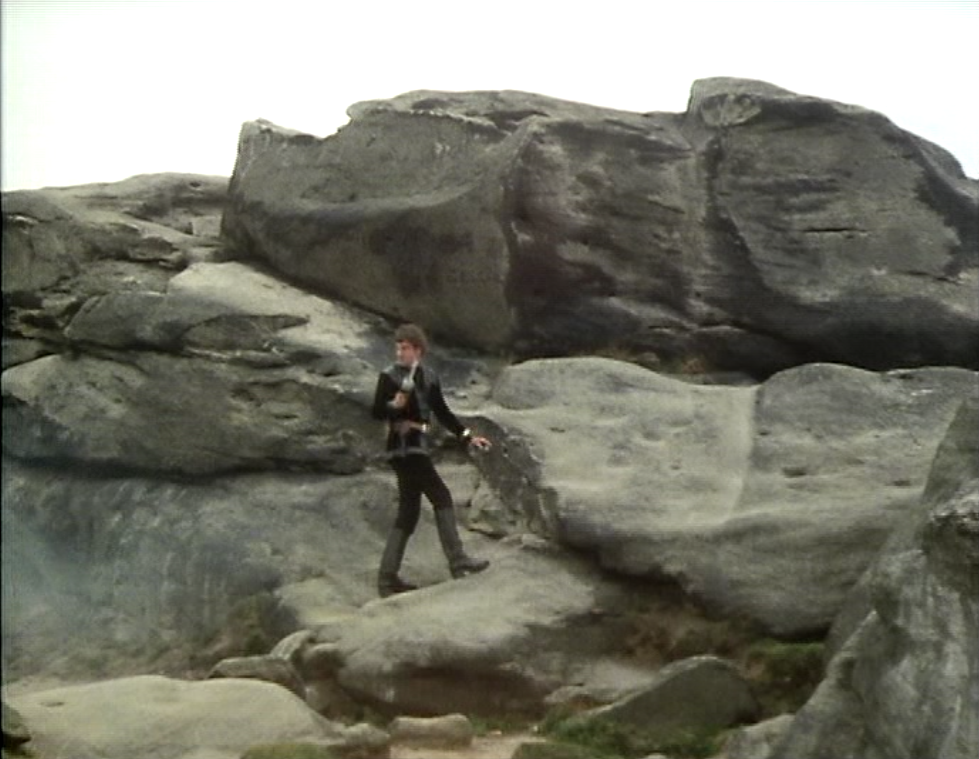 Avon stands in the middle of rocks, gun raised