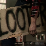 cardboard and black marker sign reads looter with man's arm hanging over it