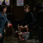 Jenny stares incredulously at Tom while Abby unpacks a cardboard box in the church