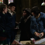 Abby, Greg and Jenny all stand listening to Tom in the church