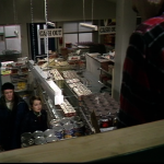 Greg and Abby look up at the swinging corpse of the so-called looter above the supermarket shelves