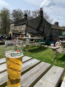 pint of heineken on a table with country cottage like pub in background