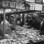 a crowd of men gathered around a large book display in waterloo station